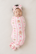 Sleeping newborn wearing the Pink Gingerbread bamboo bow headband with a big knotted bow, paired with the matching swaddle blanket