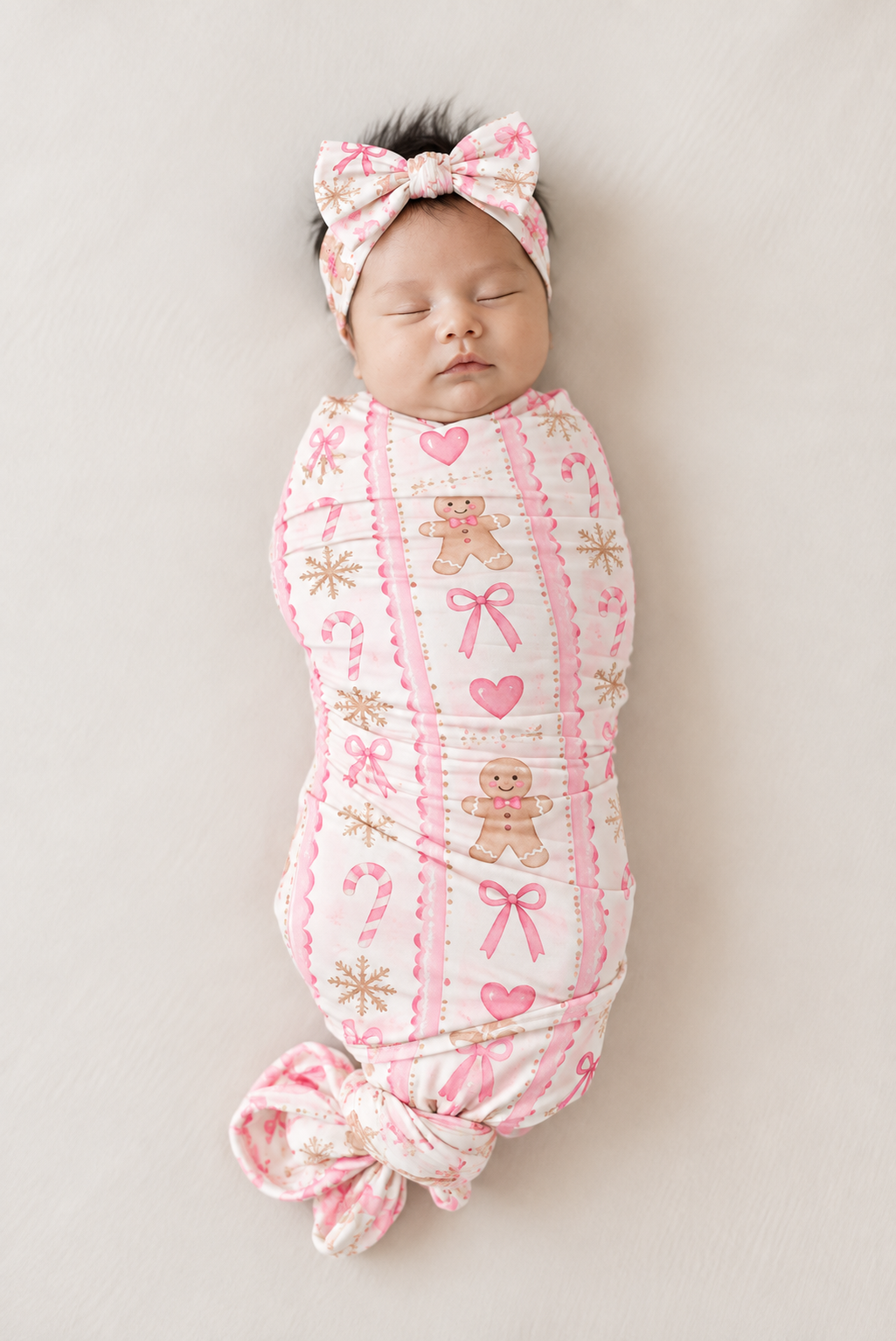 Sleeping newborn wearing the Pink Gingerbread bamboo bow headband with a big knotted bow, paired with the matching swaddle blanket