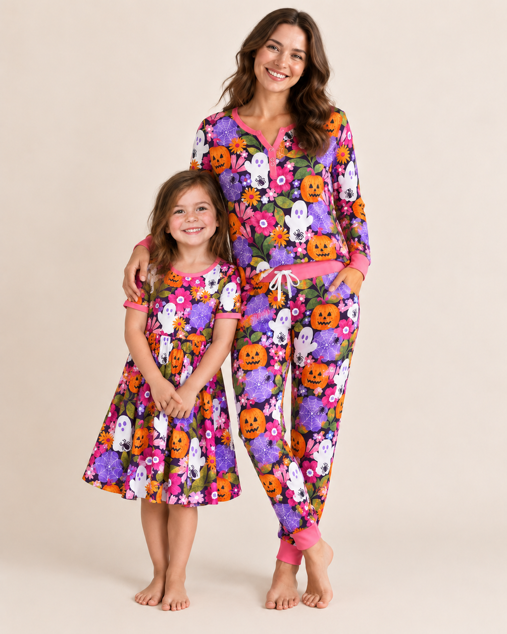 Mother and daughter in matching Pumpkin Garden Halloween pajamas — purple print with pumpkins, ghosts and flowers, hot pink trim