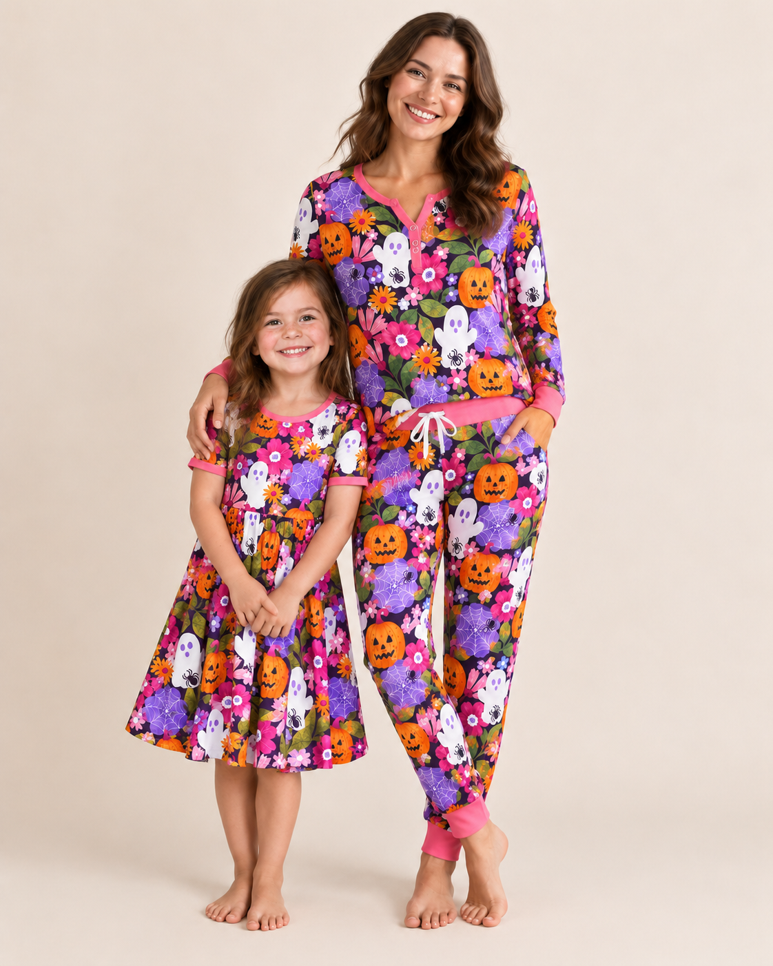 Mother and daughter in matching Pumpkin Garden Halloween pajamas — purple print with pumpkins, ghosts and flowers, hot pink trim