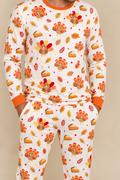Man wearing the Turkey & Pie men's long sleeve bamboo pajama set, cream with turkeys, pumpkin pie and autumn leaves, chest pocket and orange ribbed cuffs