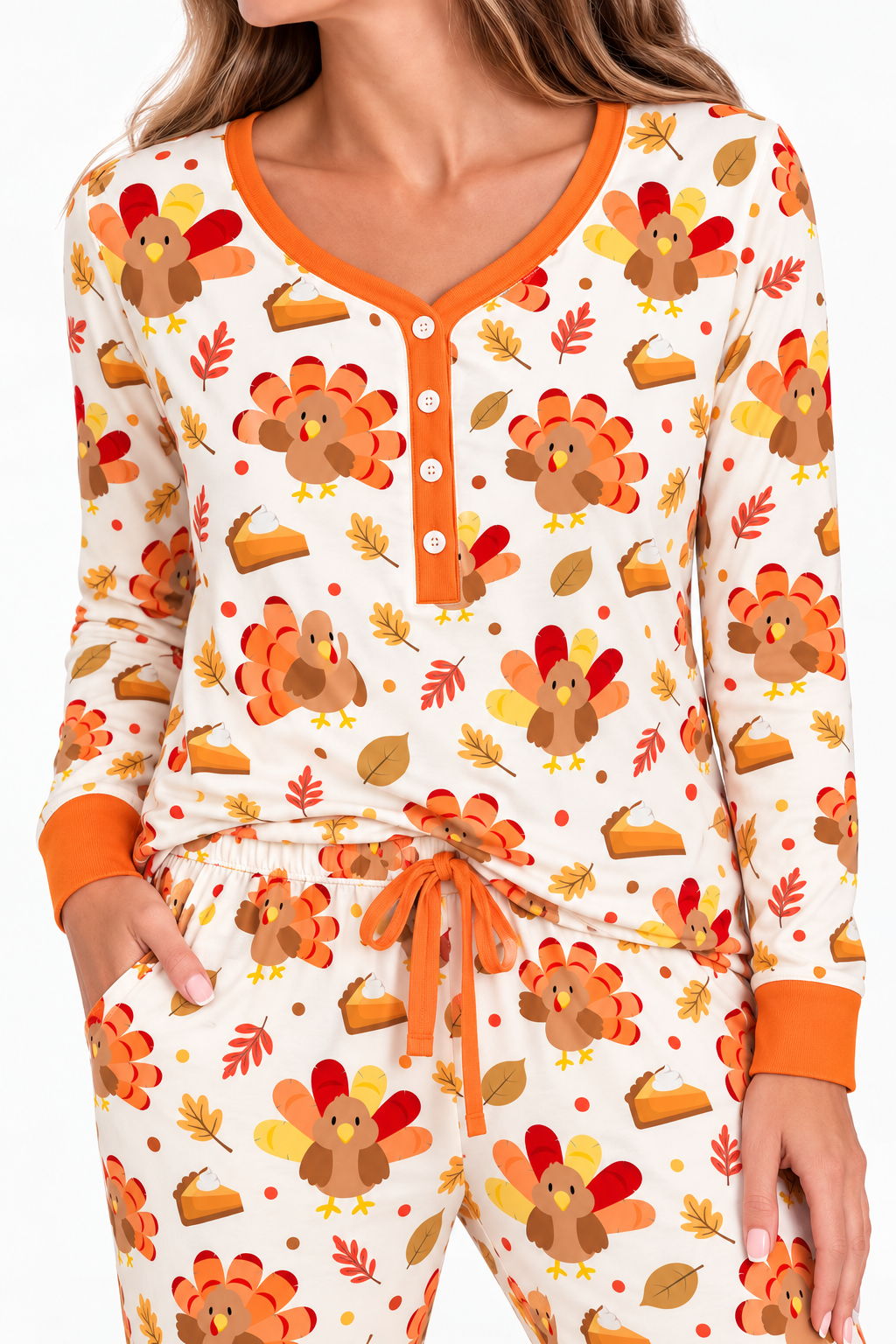 Woman wearing the Turkey & Pie women's long sleeve bamboo pajama set, cream with turkeys, pumpkin pie and autumn leaves, orange button placket, cuffs and drawstring