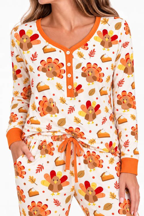 Woman wearing the Turkey & Pie women's long sleeve bamboo pajama set, cream with turkeys, pumpkin pie and autumn leaves, orange button placket, cuffs and drawstring