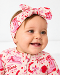 Smiling baby in the Little Texan bamboo bow headband and matching zippy, pink cowgirl boots and red roses print on cream