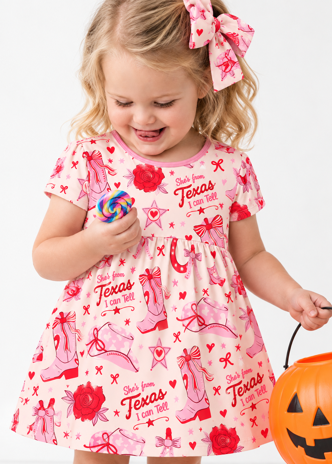 Toddler girl in the Little Texan bamboo twirl dress with pink cowgirl boots, cowboy hats and red roses on cream, pink neckline trim