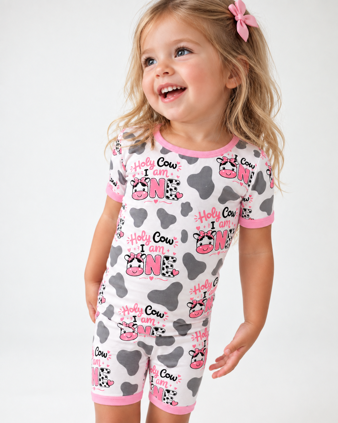 Toddler girl in a Holy Cow I'm One short sleeve bamboo pajama set with cow print and pink trim