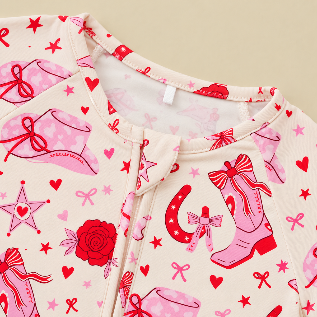 Close-up of the Little Texan bamboo zippy neckline and zipper, with pink cowgirl boots, horseshoes and heart sheriff stars