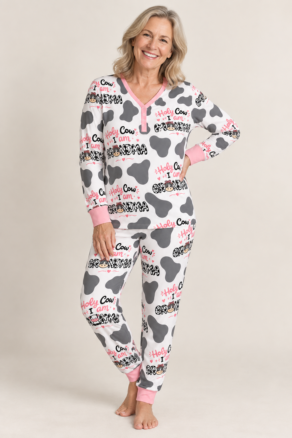Flat lay of the Holy Cow I'm Grandma women's bamboo pajama set, a V-neck henley top and joggers in grey cow print with pink trim