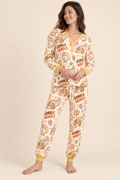 Woman wearing the Gobble Wobble Women's Bamboo Pajamas, a cream henley top and joggers printed with doodled turkeys and cornucopias, with mustard trim