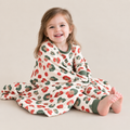 Smiling toddler in Christmas Leopard long sleeve pajamas wrapped in the matching bamboo blanket, red and green leopard spots on cream