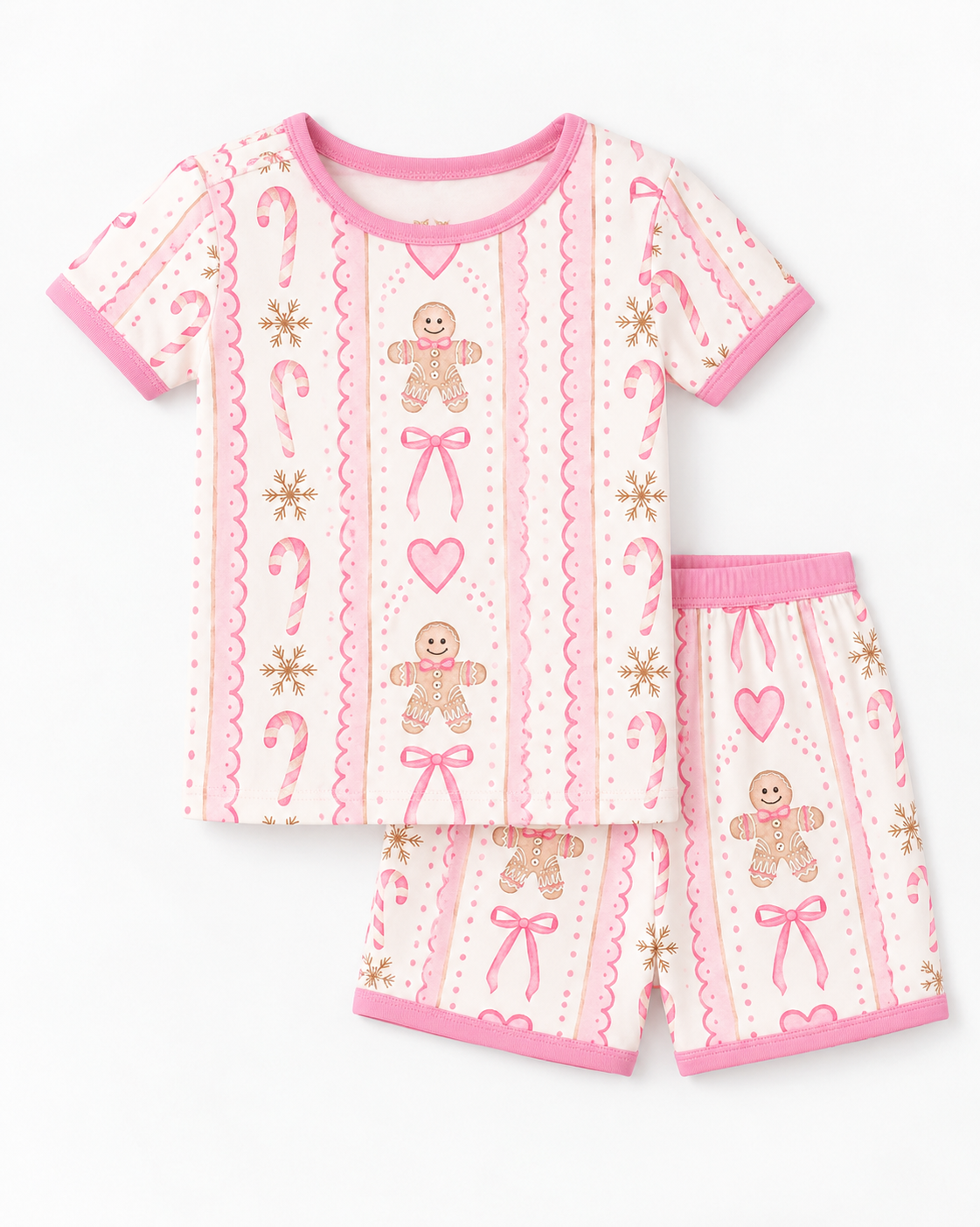 Flat lay of a pink gingerbread bamboo tee and shorts set with candy canes, hearts, snowflakes and pink scalloped ribbon stripes on cream.